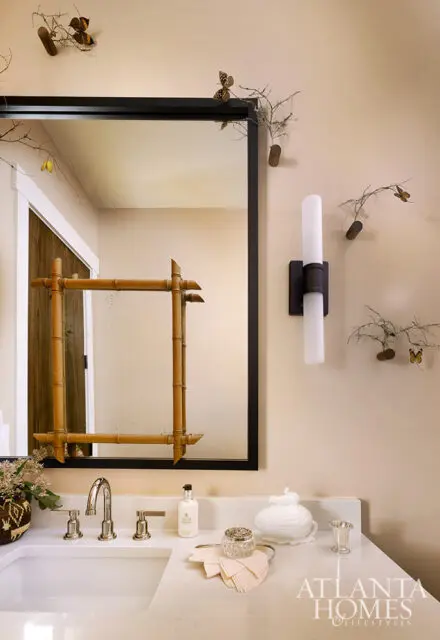 Bathroom vanity with white countertop, chrome faucet, and a mirror with a bamboo frame. Decorative
