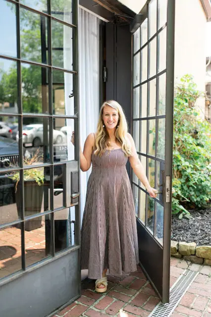 Woman in striped dress opening a glass door