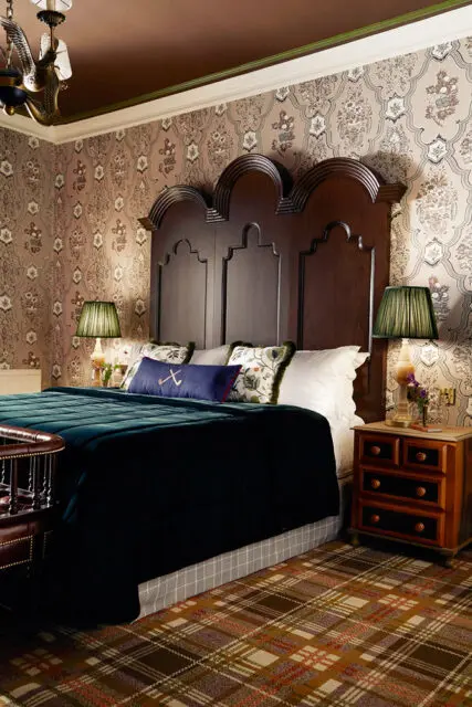 Bedroom with dark wood headboard, patterned wallpaper, and plaid carpet.