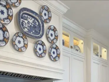 White kitchen with blue and white decorative plates on wall and stainless steel range
