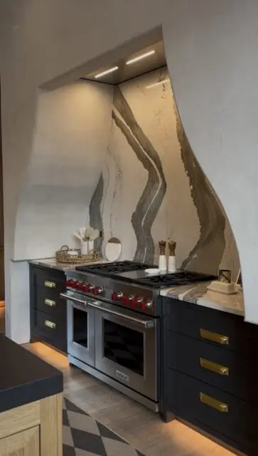 Modern kitchen with stainless steel range, black cabinets, and a marble backsplash with gray