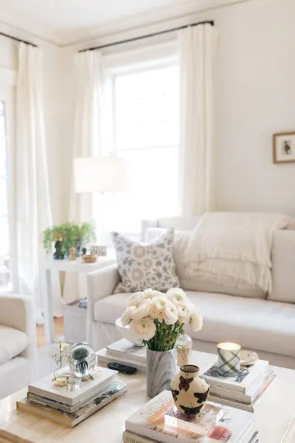 Living room with white sofa, patterned pillows, and coffee table with books and flowers