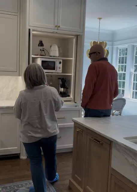 White kitchen with built-in appliance cabinet, marble countertops, and wood island.