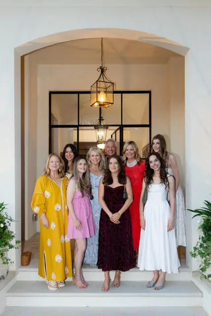 Group of ten people posing on steps in front of an arched entryway with lanterns