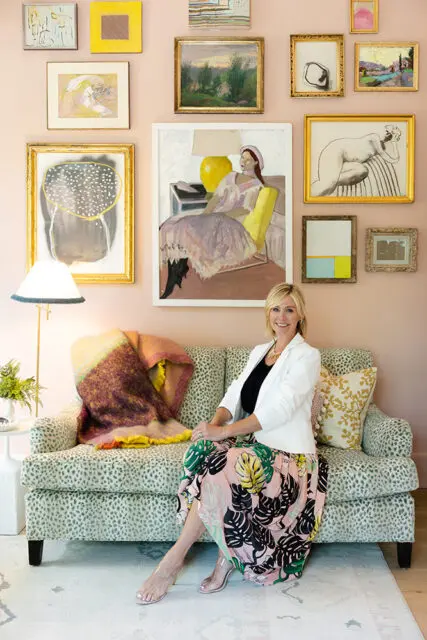 Woman in white blazer and floral skirt sitting on leopard print sofa with colorful blanket.