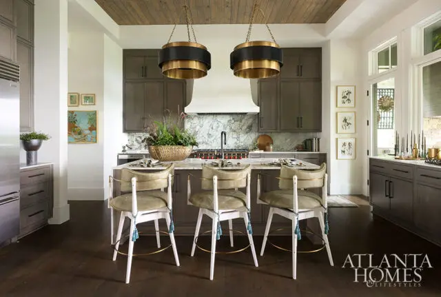 Gray kitchen with marble backsplash, island with bar stools, and wood ceiling.