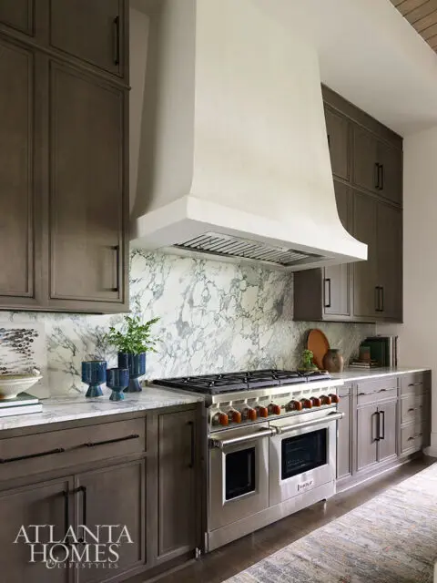 Dark wood cabinets, marble backsplash, and stainless steel range with a cream hood.