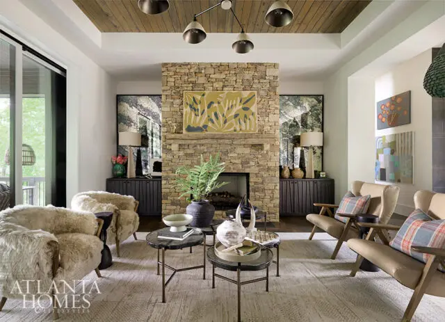 Living room with stone fireplace, wood ceiling, plush chairs, and leather armchairs.
