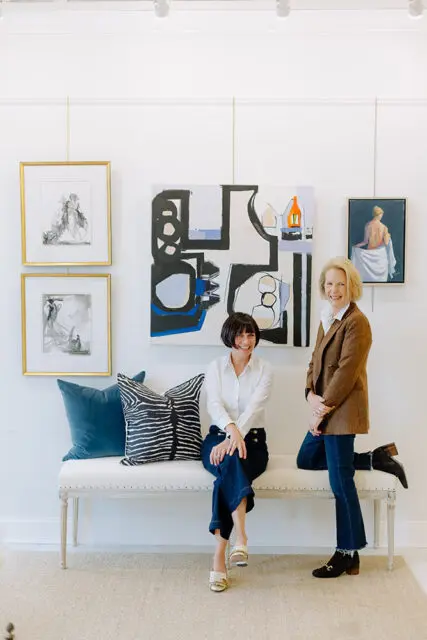 Meg Harrington and Ann Huff seated and standing in front of artwork.