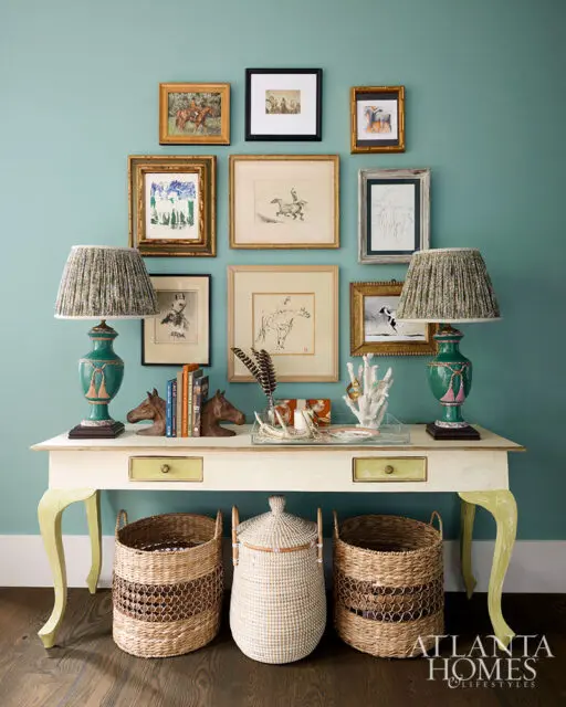 Console table with equestrian art, green lamps, and woven baskets