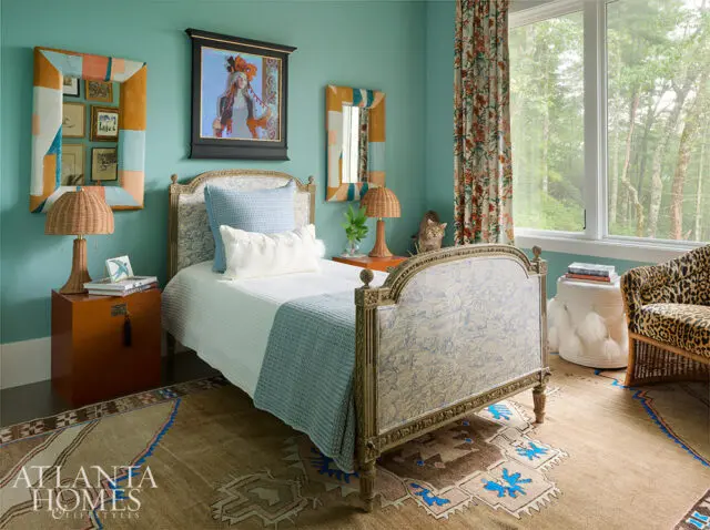 Bedroom with teal walls, a carved bed with blue patterned upholstery, and a leopard print chair.