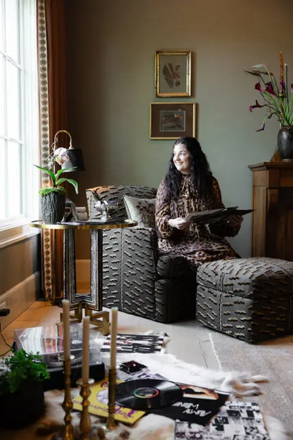 Woman in leopard print dress holding records in a room with patterned furniture