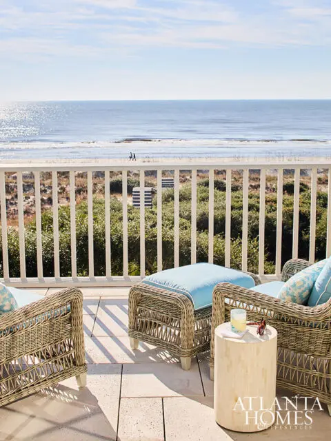 Wicker patio furniture on a balcony overlooking the ocean, with Atlanta Homes & Lifestyles logo