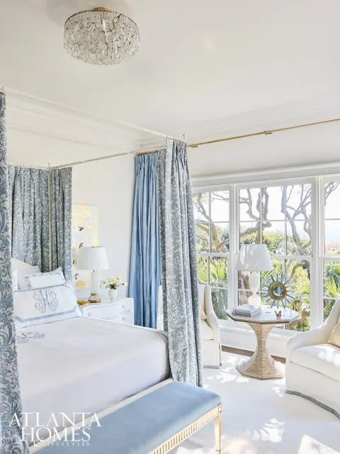 Bedroom with a four-poster bed, blue damask curtains, and a crystal chandelier.