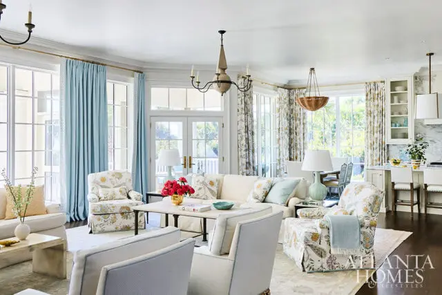 Living room with floral armchairs, light blue curtains, and a cream sofa.