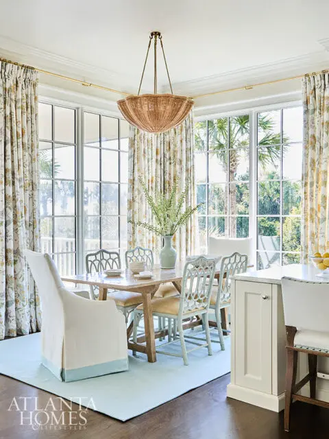 Dining room with light blue rug, wood table, and chairs with ornate backs.