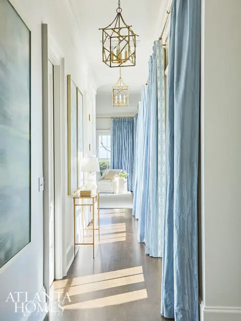 Hallway with light blue curtains, gold lanterns, and artwork.