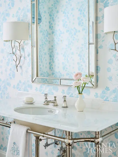 Blue floral wallpaper, white marble vanity with silver faucet, and a mirrored cabinet.