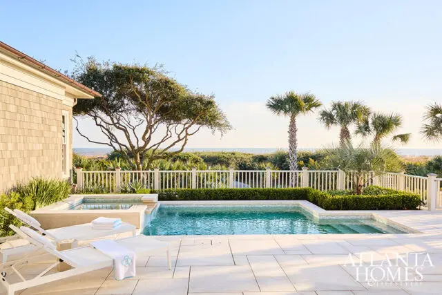 Pool and spa with lounge chairs overlooking the ocean, palm trees, and a large tree
