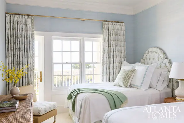 Bedroom with twin beds, blue grasscloth wallpaper, and floral curtains.