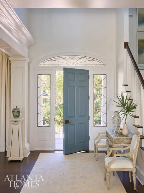 Foyer with blue double doors, arched transom window, and ornate console table.
