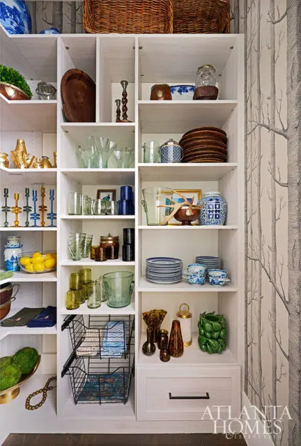 White shelving unit filled with decorative items including glassware, plates, and vases