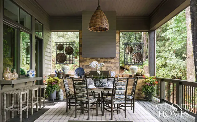 Covered porch with dining table, chairs, bar stools, and stone fireplace.