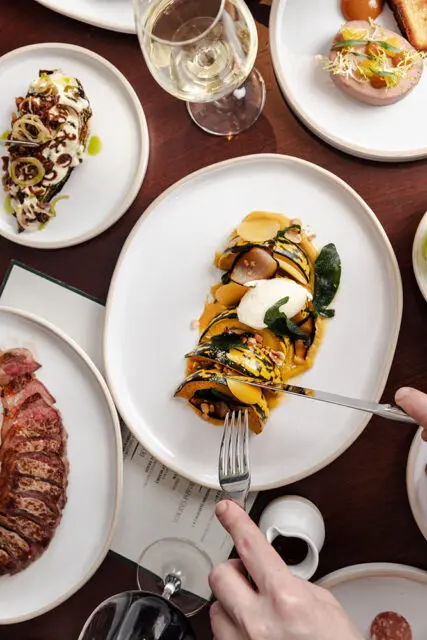 Sliced delicata squash with dollop of cream and nuts on white plate