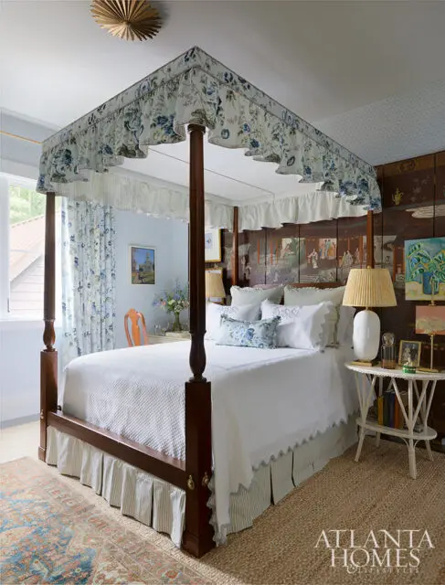 Bedroom with four-poster bed, floral canopy, white bedding, and chinoiserie screen