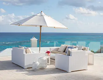 White wicker patio furniture with umbrella and ocean view