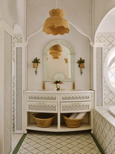 White bathroom vanity with rattan pendant light and green patterned tile floor