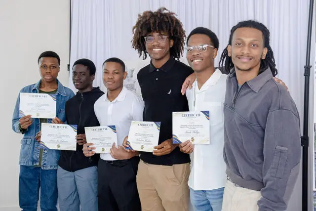 Six young men stand holding certificates. Jacob Jackson, Amsu Re Eatman, Samuel Washington