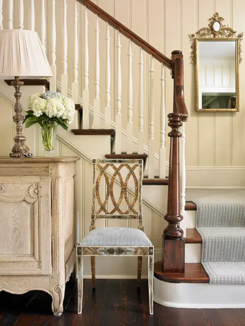 Entryway with ornate chair, antique dresser, staircase, and mirror