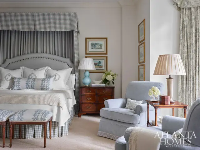 Bedroom with upholstered bed, blue and white patterned pillows, and sitting chairs.