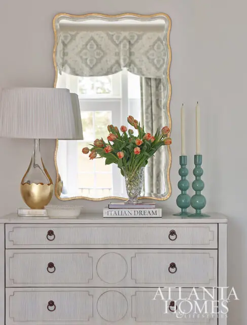 White dresser with ornate mirror, tulips, and lamp