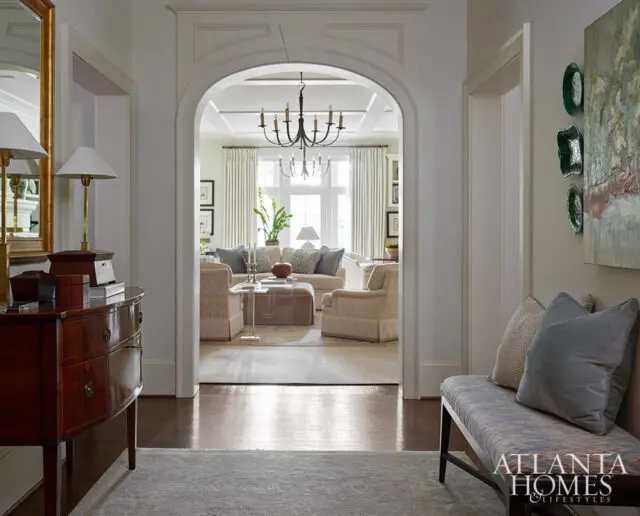 Hallway with arched doorway to living room, antique dresser, and bench.