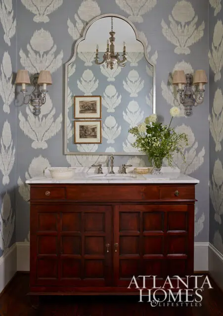 Powder room with blue ikat wallpaper, dark wood vanity, and marble countertop.