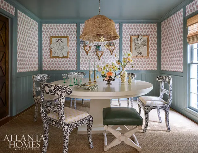 Dining room with oval table, patterned chairs, floral centerpiece, and patterned wallpaper.