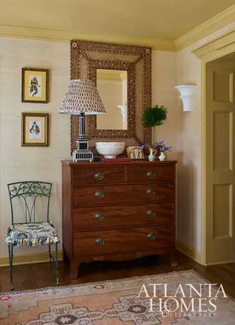 Mahogany chest of drawers with brass hardware, patterned lamp, and woven mirror