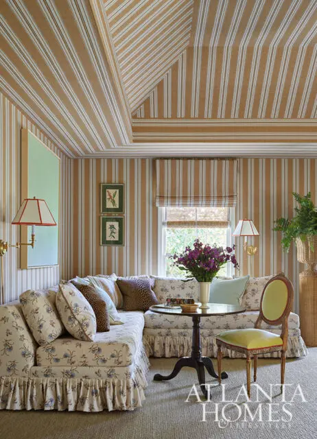 Living room with striped wallpaper and ceiling, floral sectional sofa, and green chair.