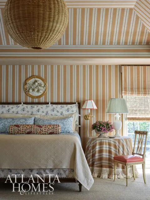 Bedroom with striped wallpaper, a large wicker pendant light, and a bed with floral and striped
