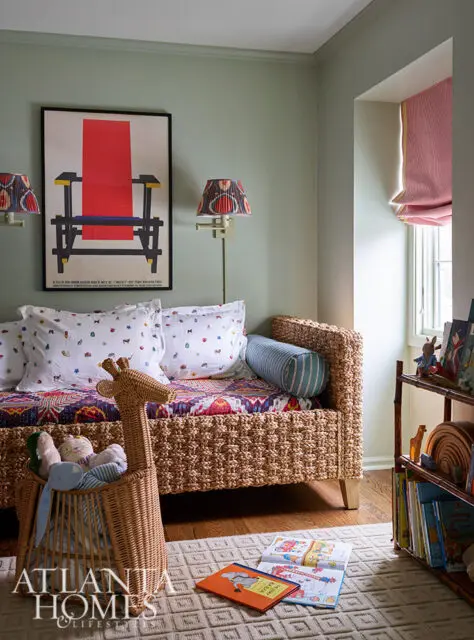Wicker daybed with patterned pillows and a giraffe basket. Artwork and books visible.