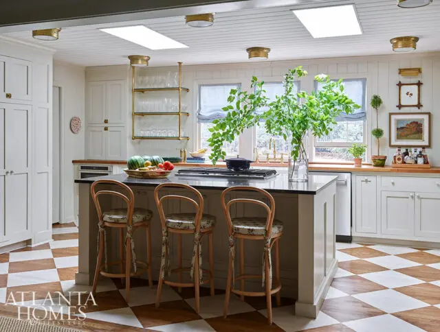 White kitchen with island, checkered floor, and bar stools.