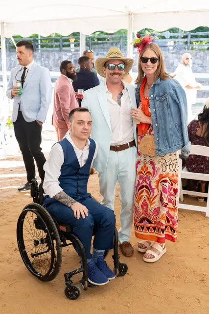 Man in wheelchair with tattoos, man in straw hat and light blue suit, woman in patterned dress and