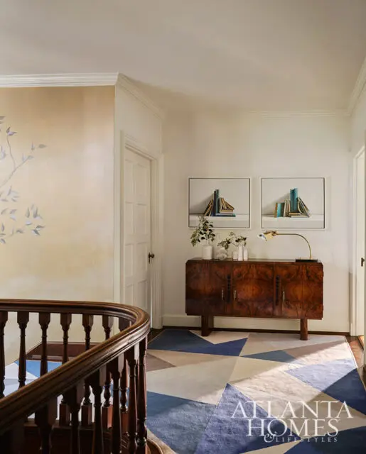 Hallway with geometric rug, wood cabinet, and artwork. Atlanta Homes & Lifestyles logo visible.