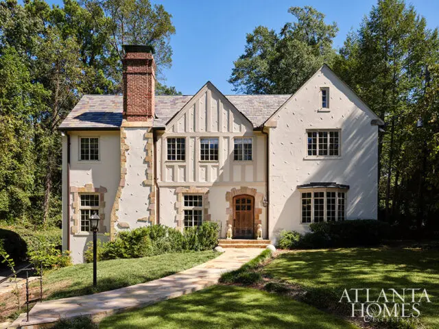 Tudor-style house with stucco exterior, stone accents, and slate roof.