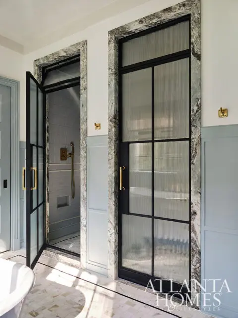 Bathroom with fluted glass doors, marble trim, and gold hardware. Shower visible.