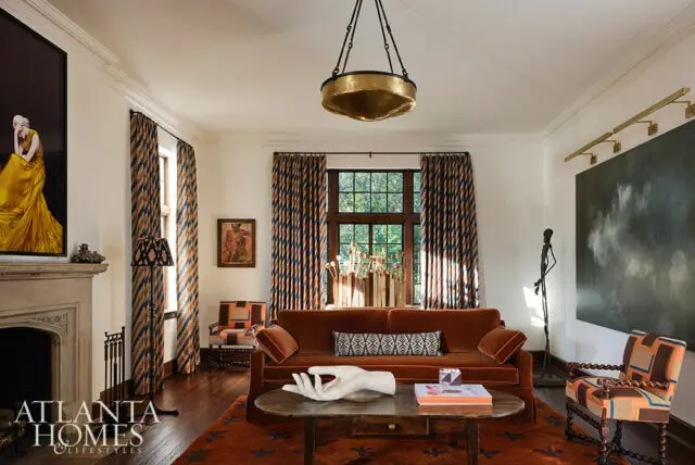 Living room with rust-colored sofa, patterned curtains, fireplace, and artwork.
