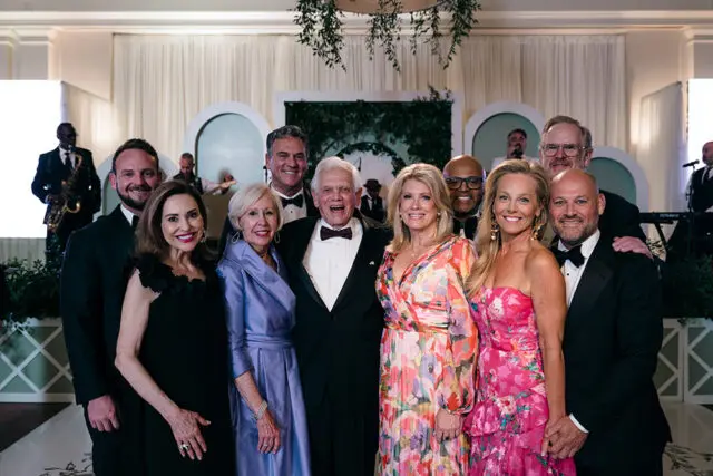 Group of people in formal attire posing for a photo at an event.