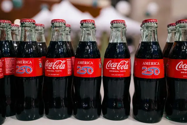 Coca-Cola bottles with red labels featuring 'America 250' and 'Original Taste'
